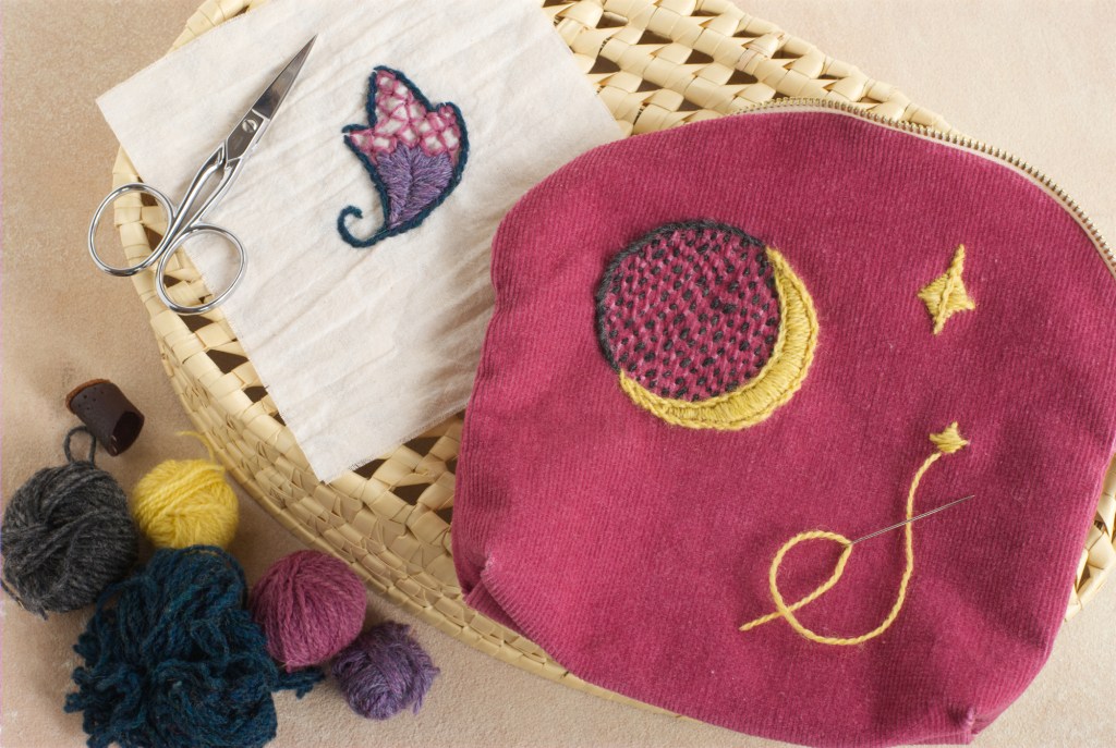 Embroidery of a crescent moon and stars next to a traditional Swedish leaf motif